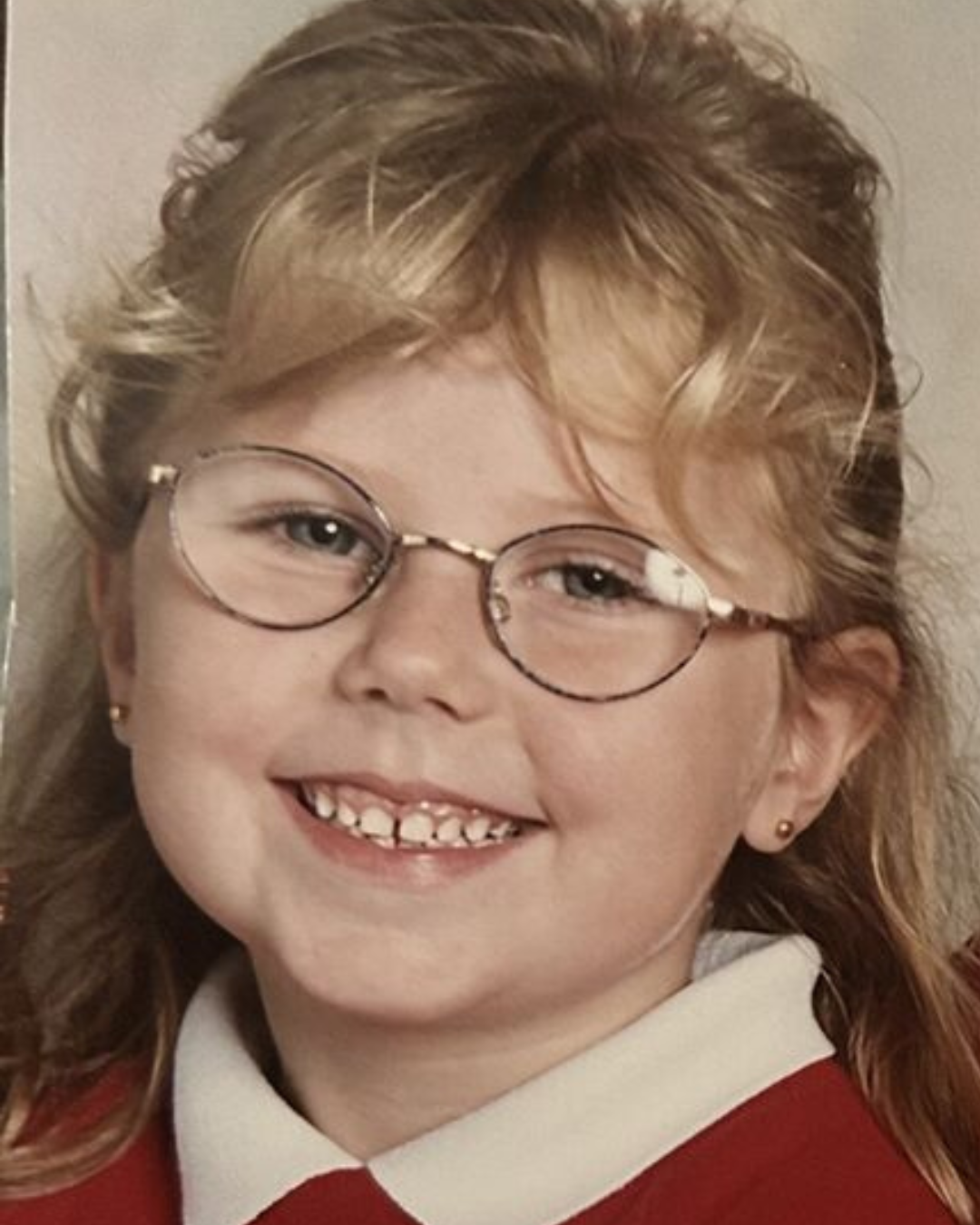 Claire as a young girl in school uniform, smiling with glasses