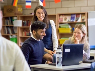 Teachers gather round a laptop