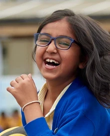 A pupil laughing while running through a school playground.