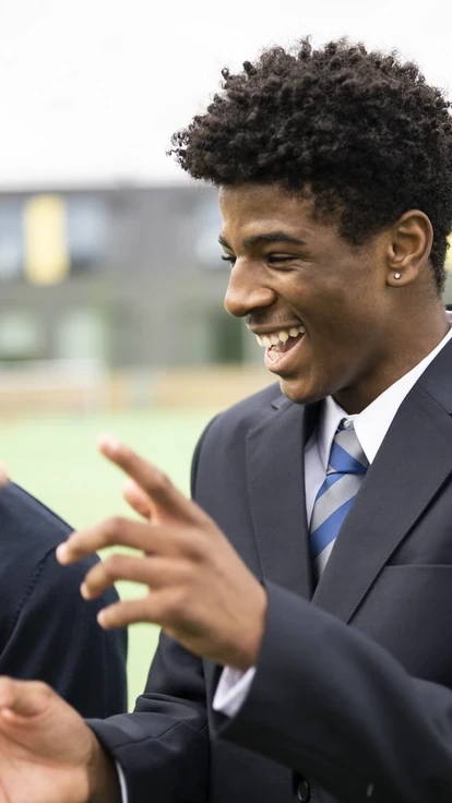 Two pupils sharing a laugh on a playing field.