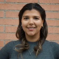 Louise, a Summer Project participant, smiling in front of a brick wall.